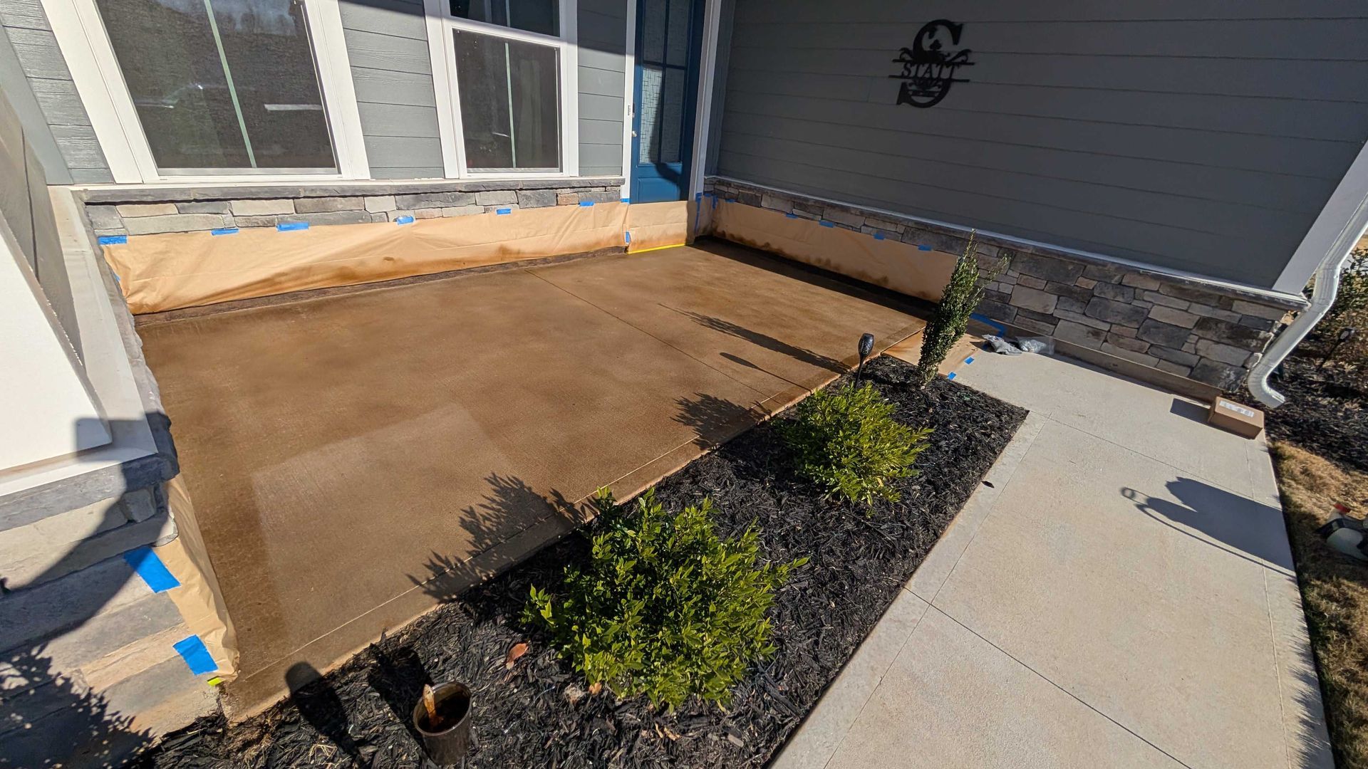 A concrete patio is being built in front of a house.