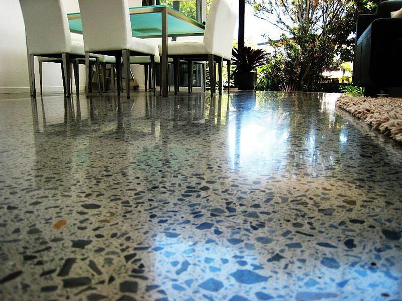 A dining room with a table and chairs and a shiny concrete floor
