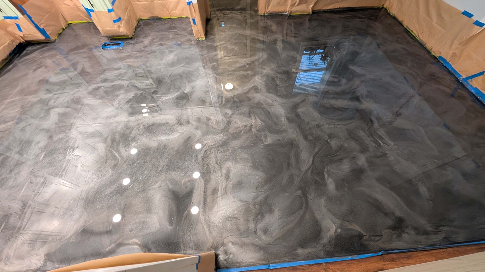 A black and silver metallic floor is being painted in a room.