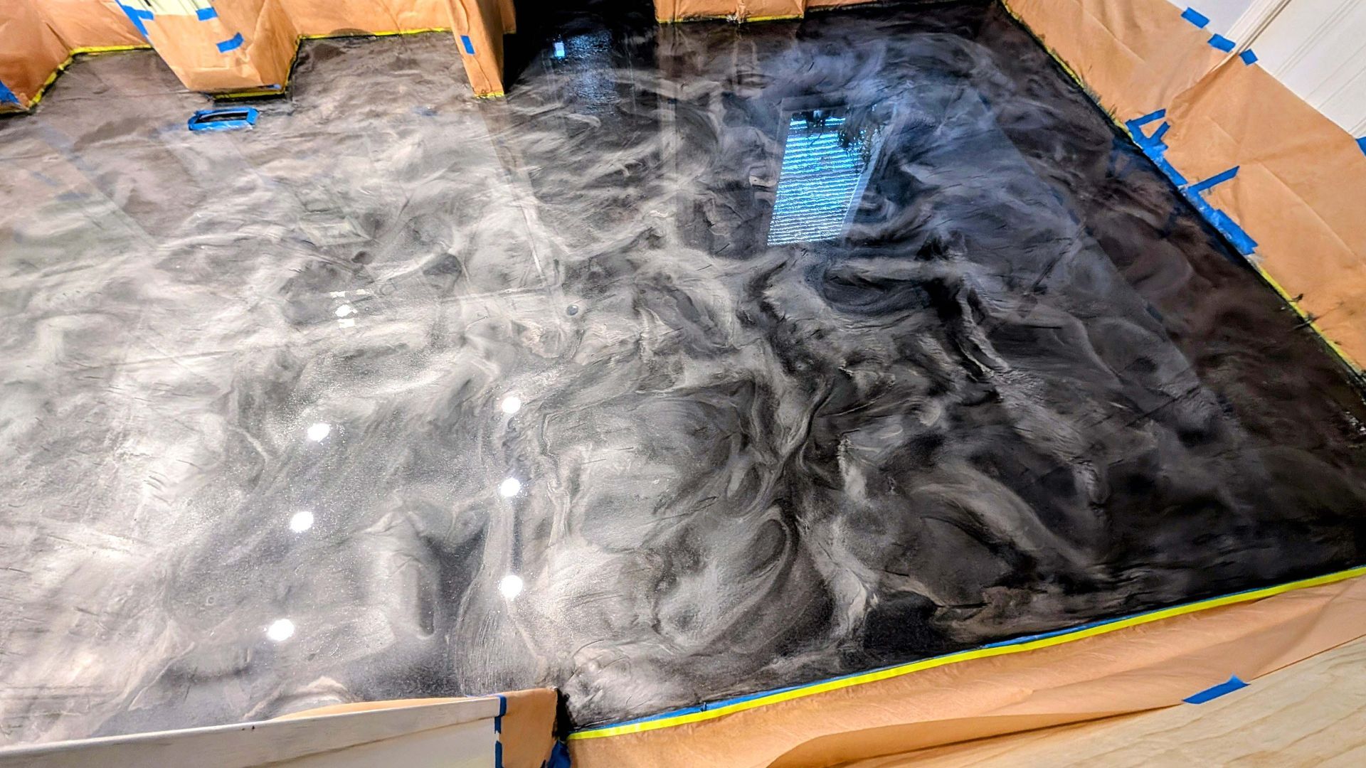 A black and silver metallic floor is being painted in a room.