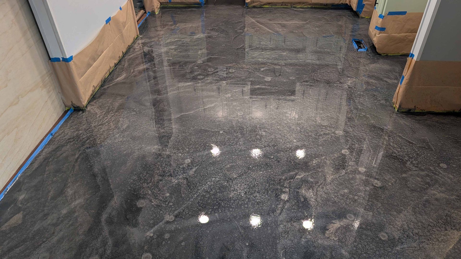 A kitchen with a shiny metallic floor and cabinets.