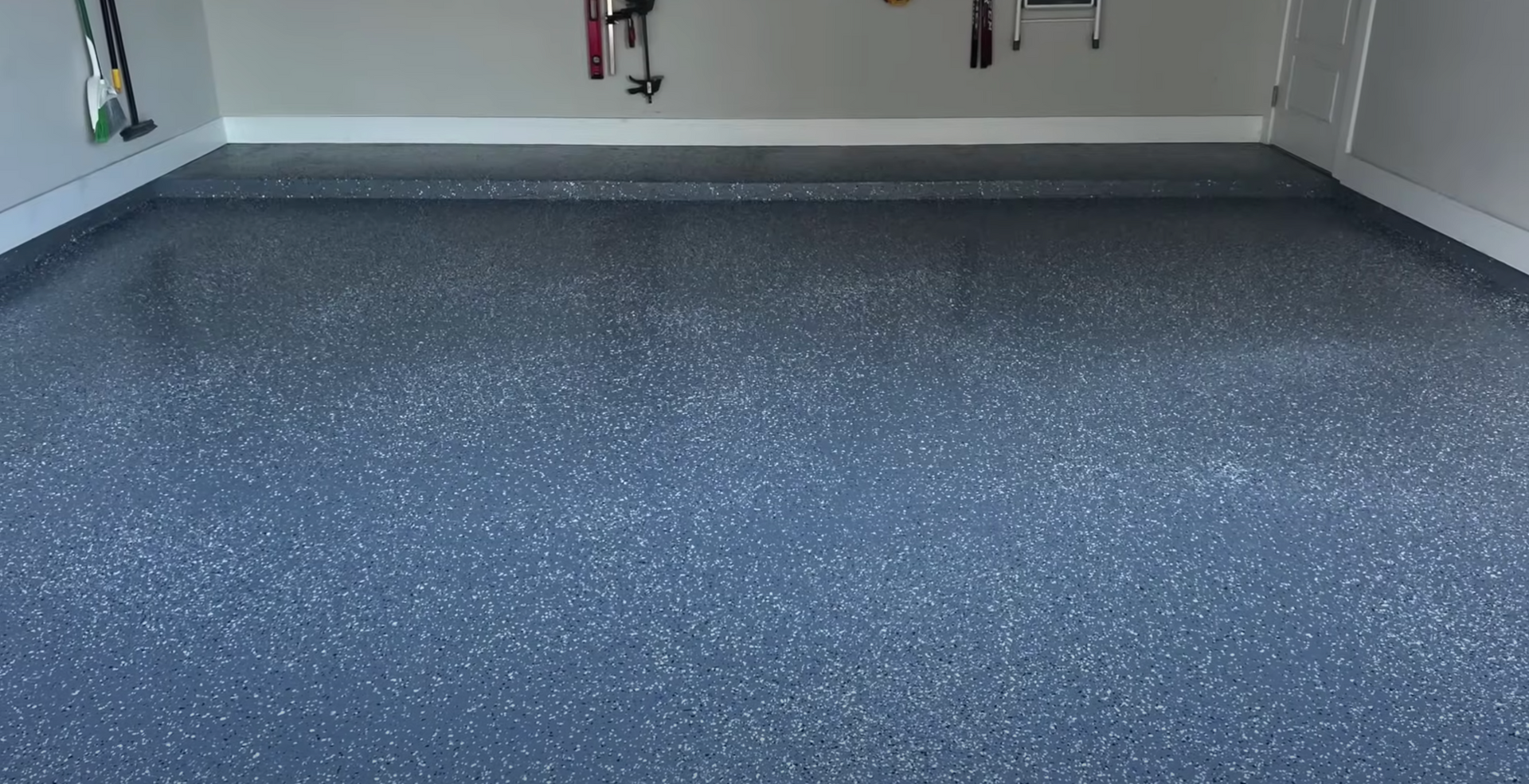A garage floor with a lot of tools hanging on the wall.