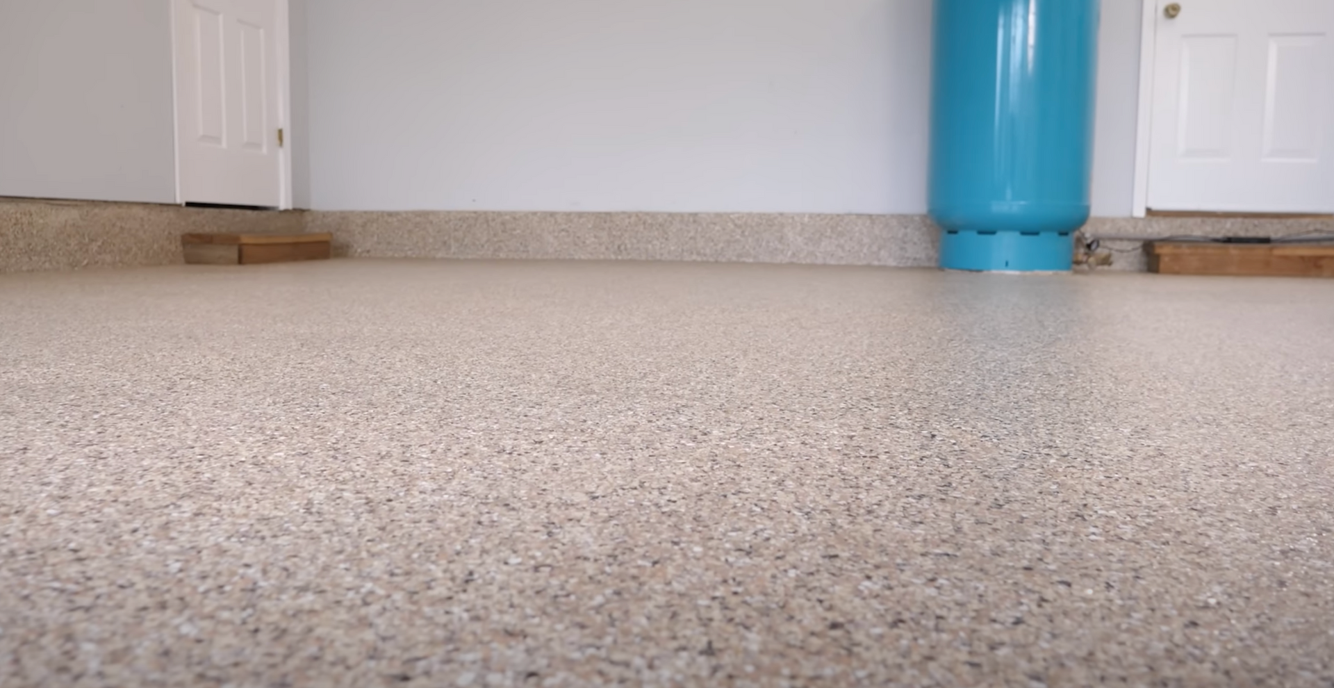 A close up of a garage floor with a blue tank in the background.