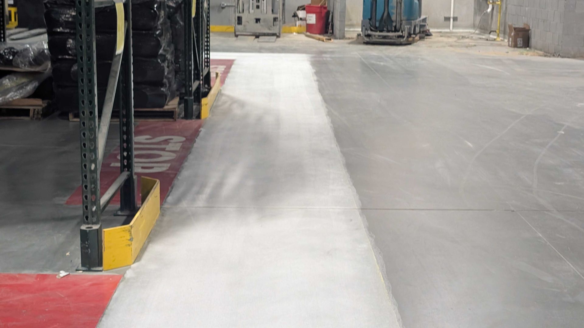 A forklift is driving down a concrete road in a warehouse.