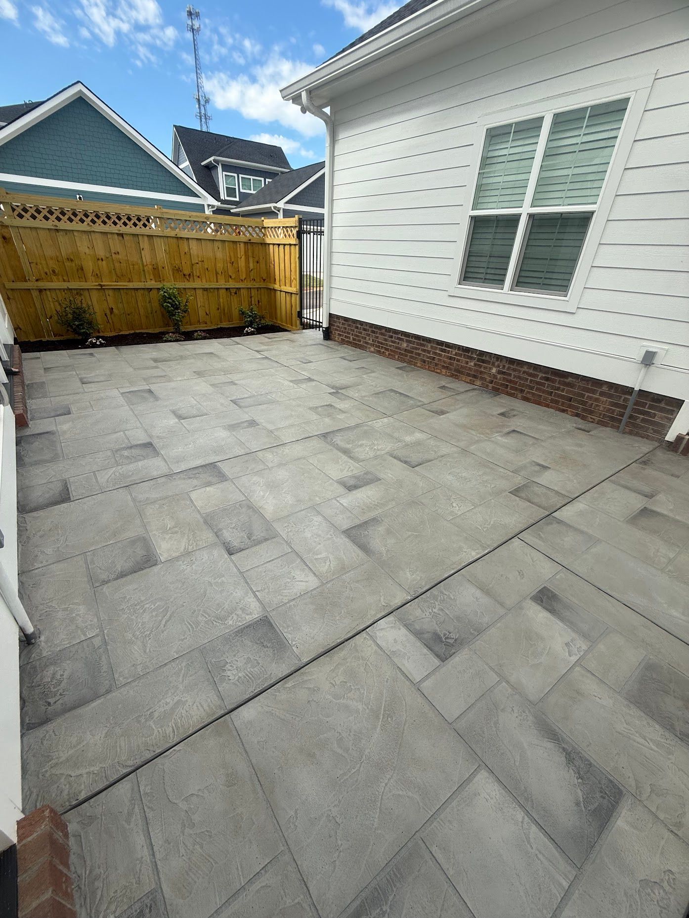 There is a patio in front of a house with a wooden fence.