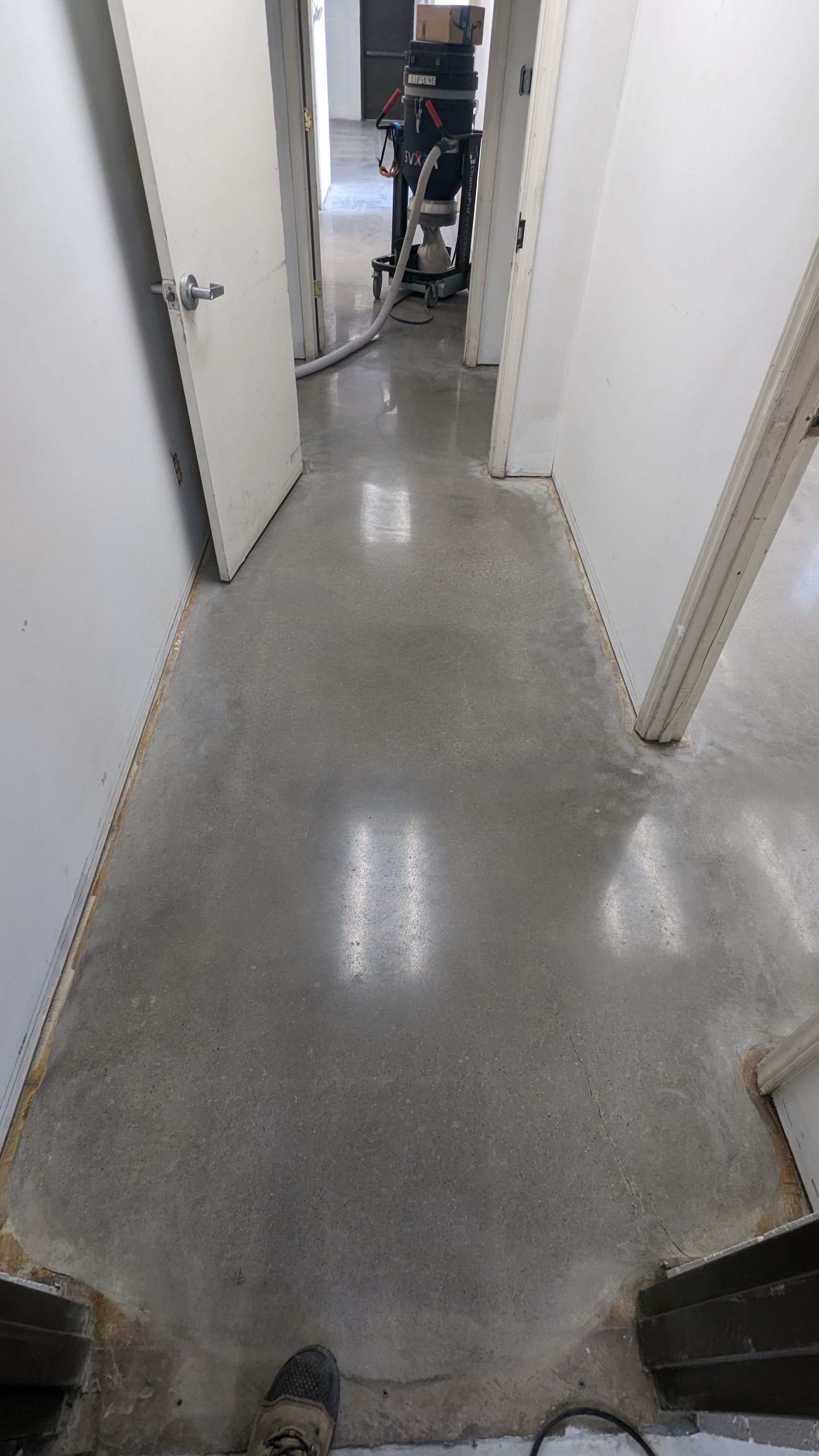 A hallway with a concrete floor and a vacuum cleaner.