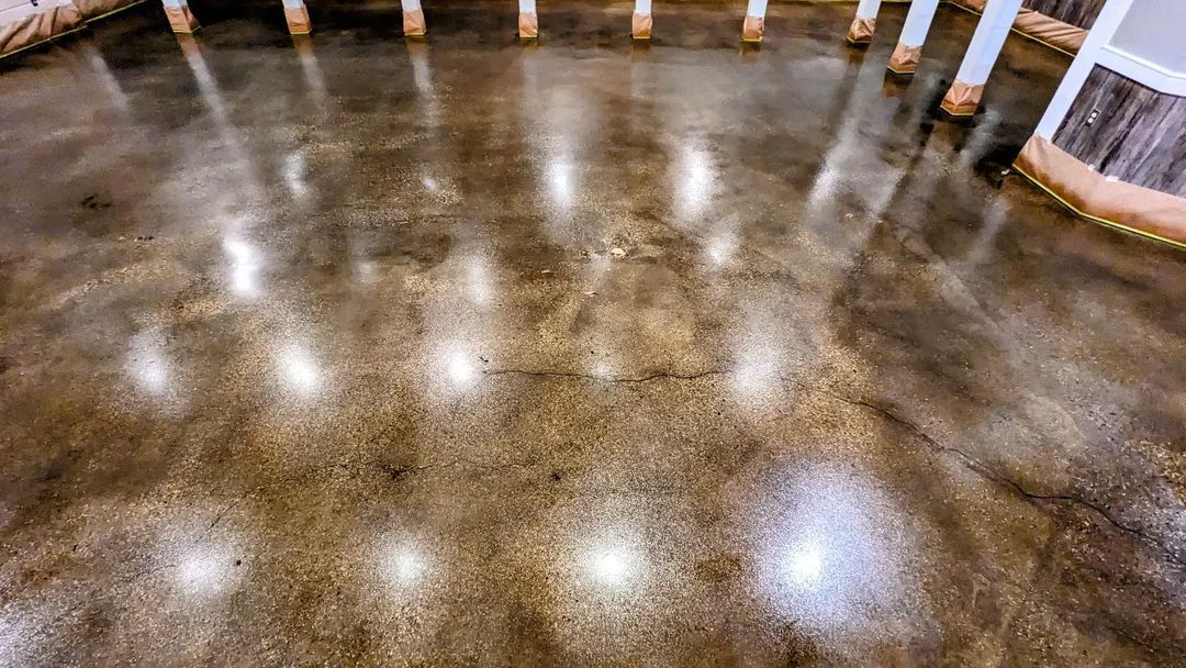 A close up of a shiny concrete floor with lights reflecting off of it.