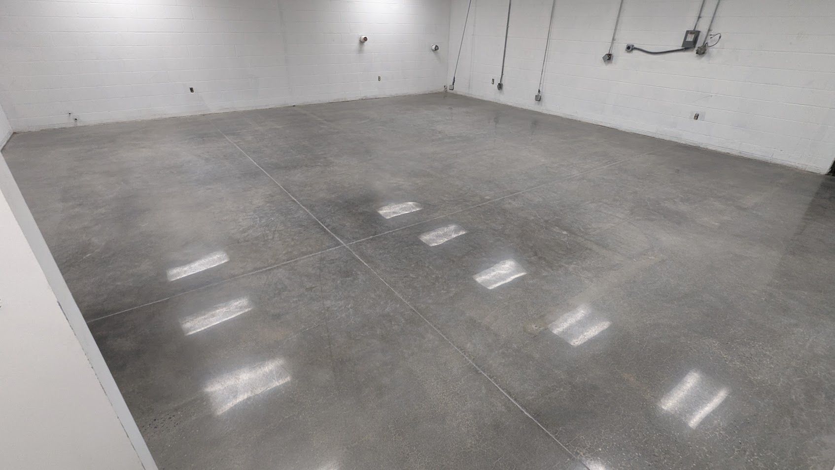A large room with a stained concrete floor and wooden walls.