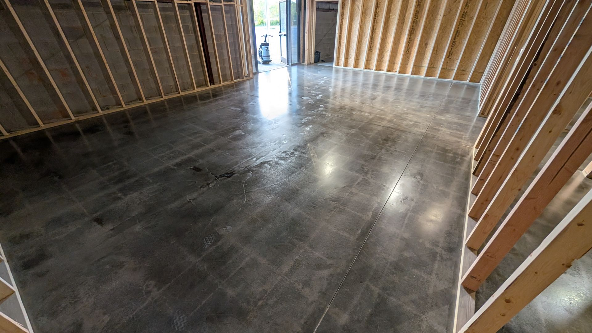 Freshly finished metallic epoxy floor in a residential room with swirled patterns and protective tape along the walls.