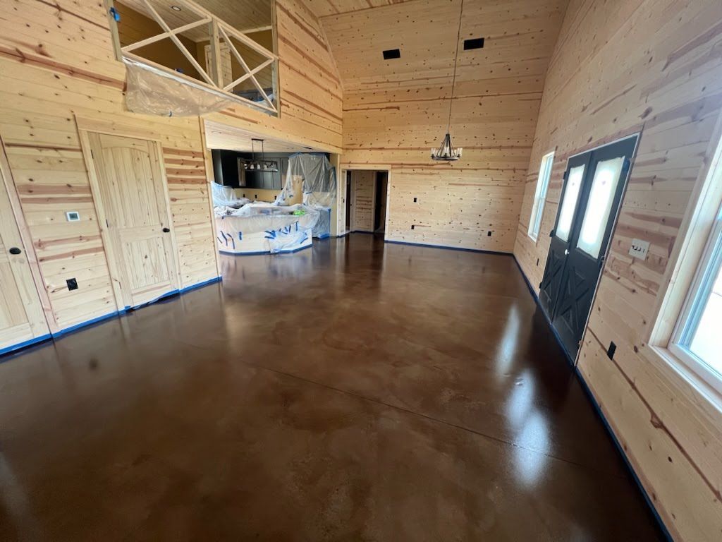 A large room with a stained concrete floor and wooden walls.