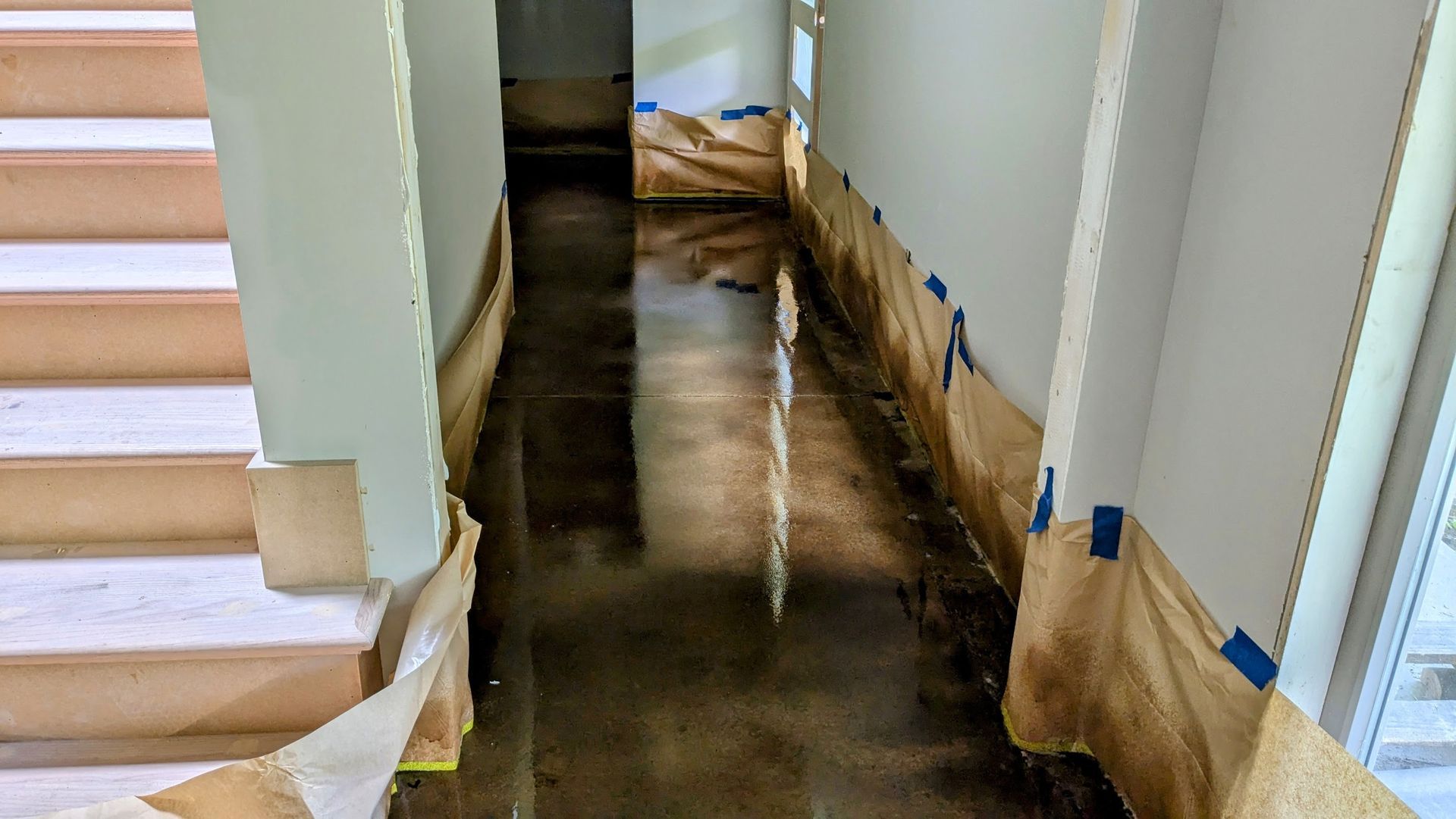 A hallway with stairs and a flooded floor in a house.