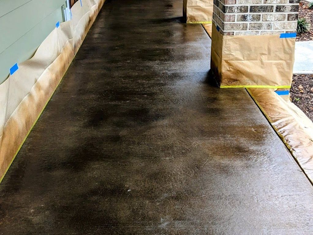 A concrete walkway with a brick wall and pillars in the background.