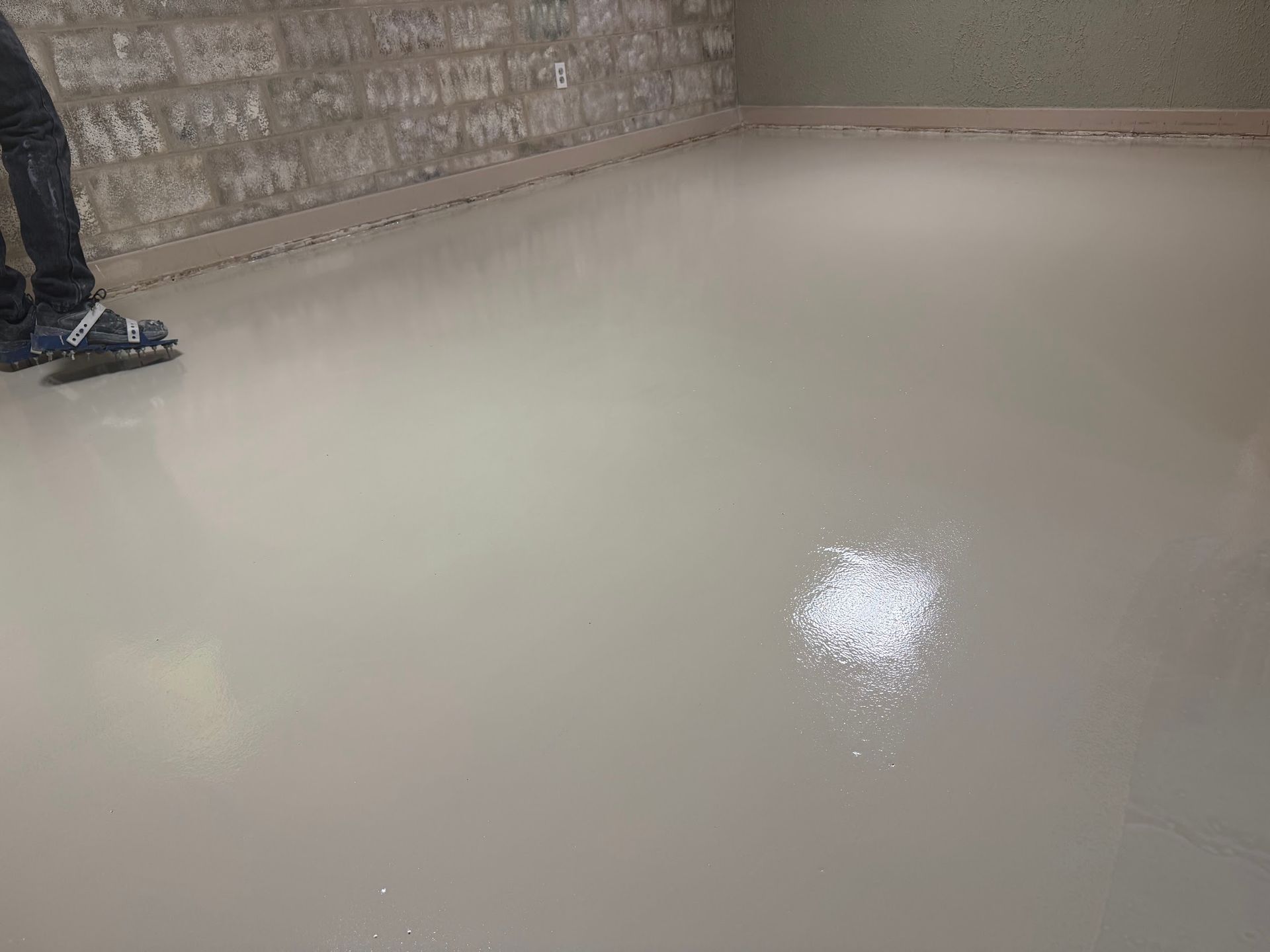 Freshly finished metallic epoxy floor in a residential room with swirled patterns and protective tape along the walls.