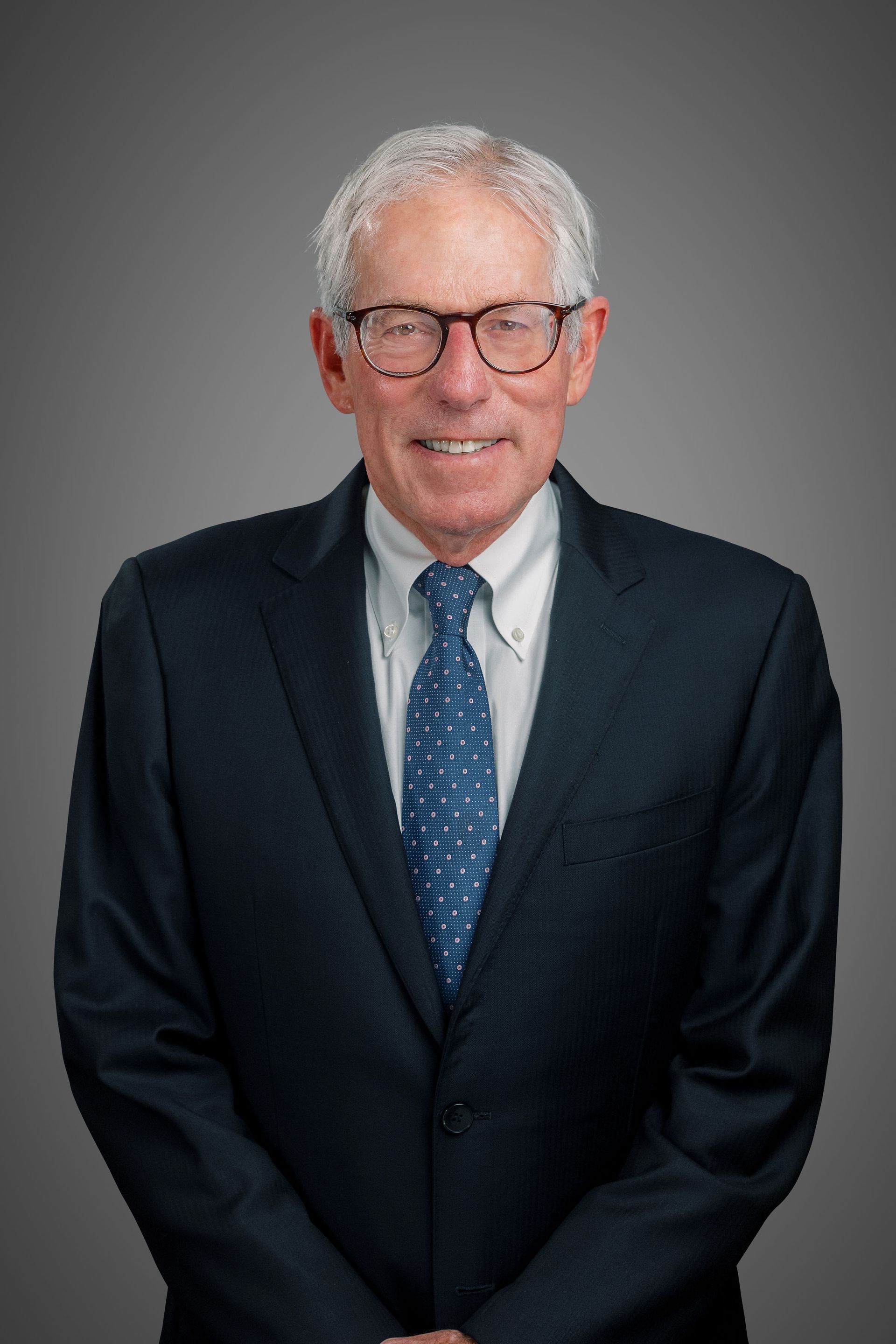 A Super Lawyer in a suit and tie is smiling with his hands in his pockets.