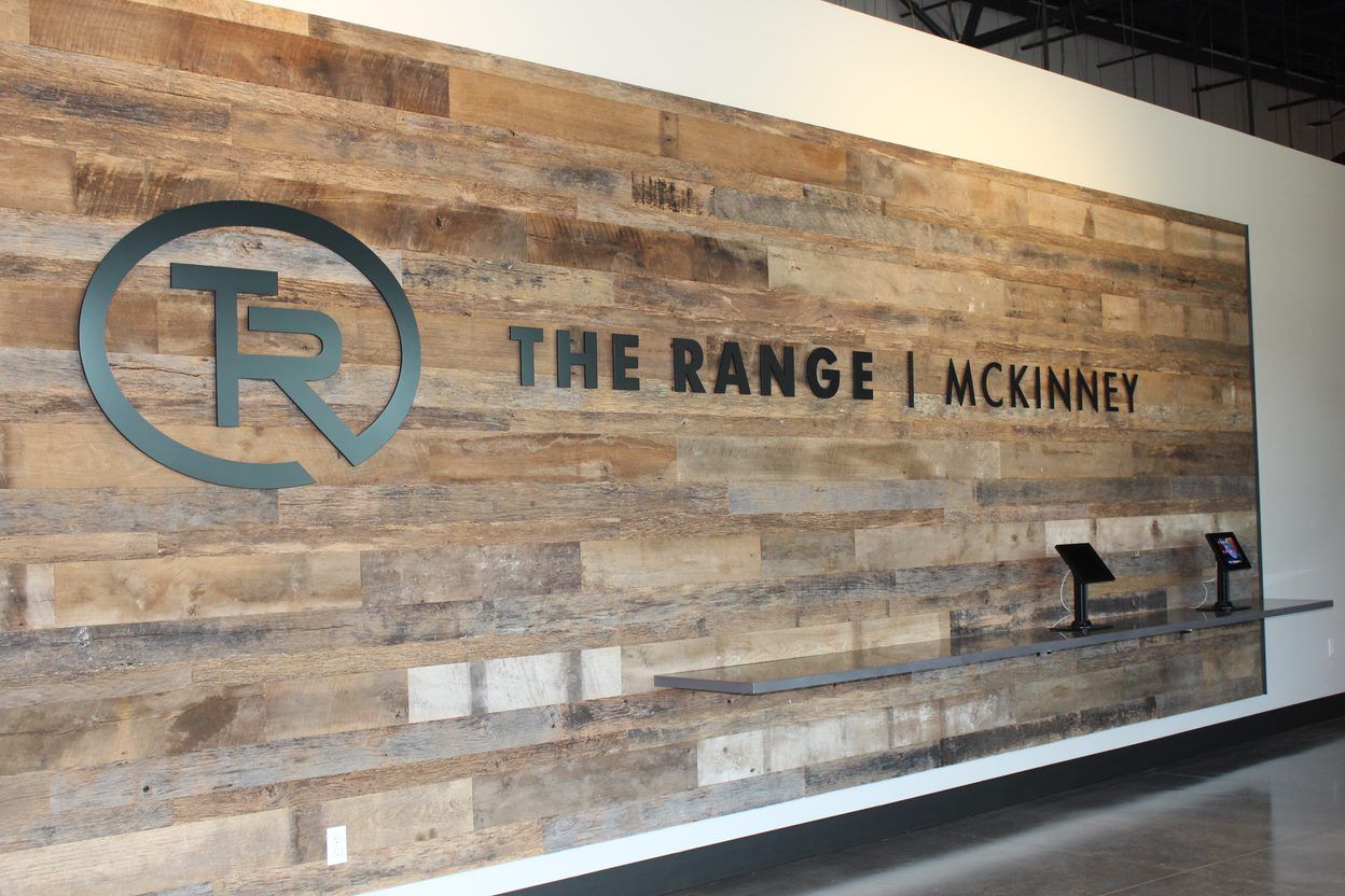The Range in McKinney logo on a wood accent wall
