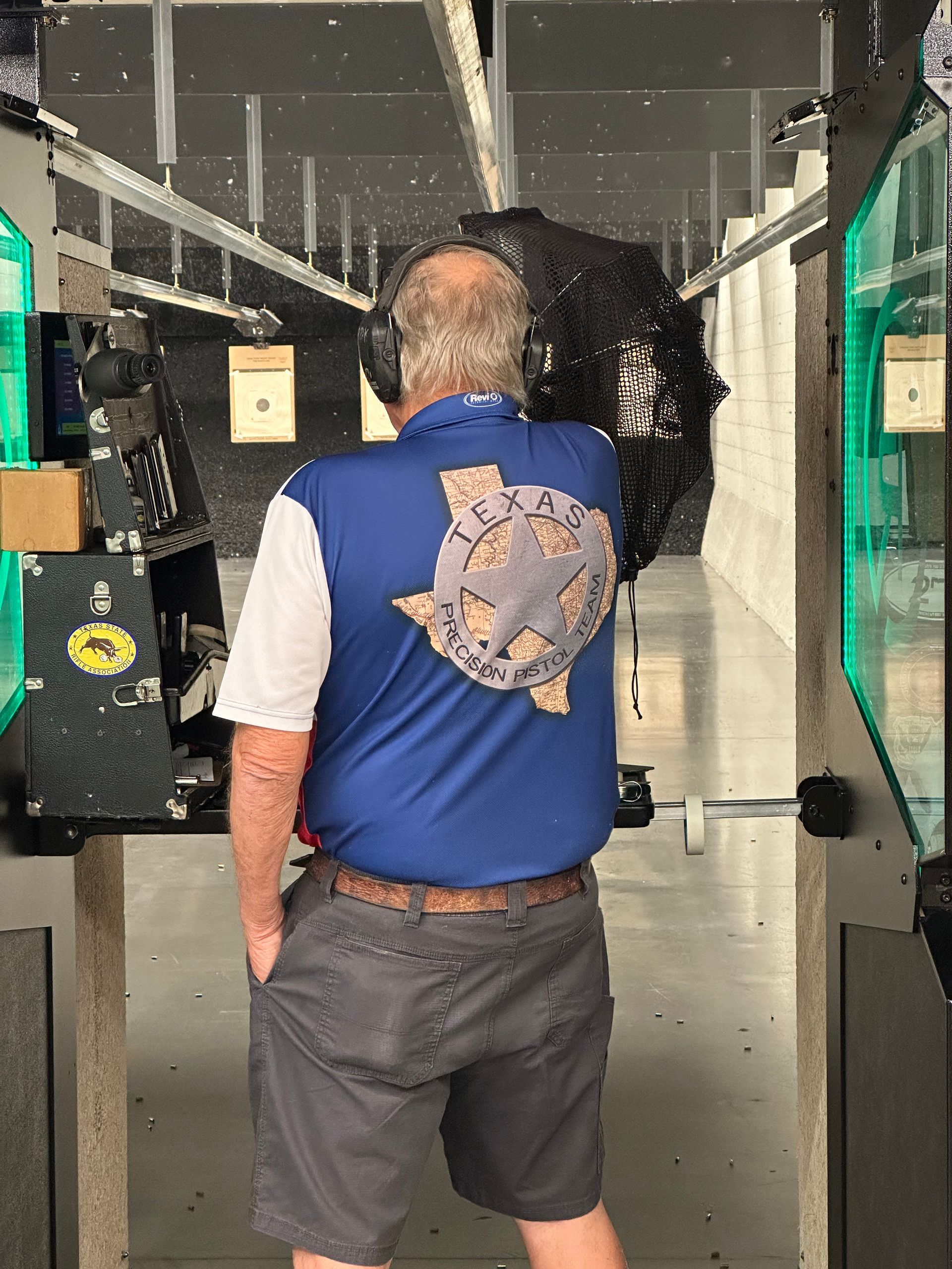 Man in a vest shooting at a green-lit lane
