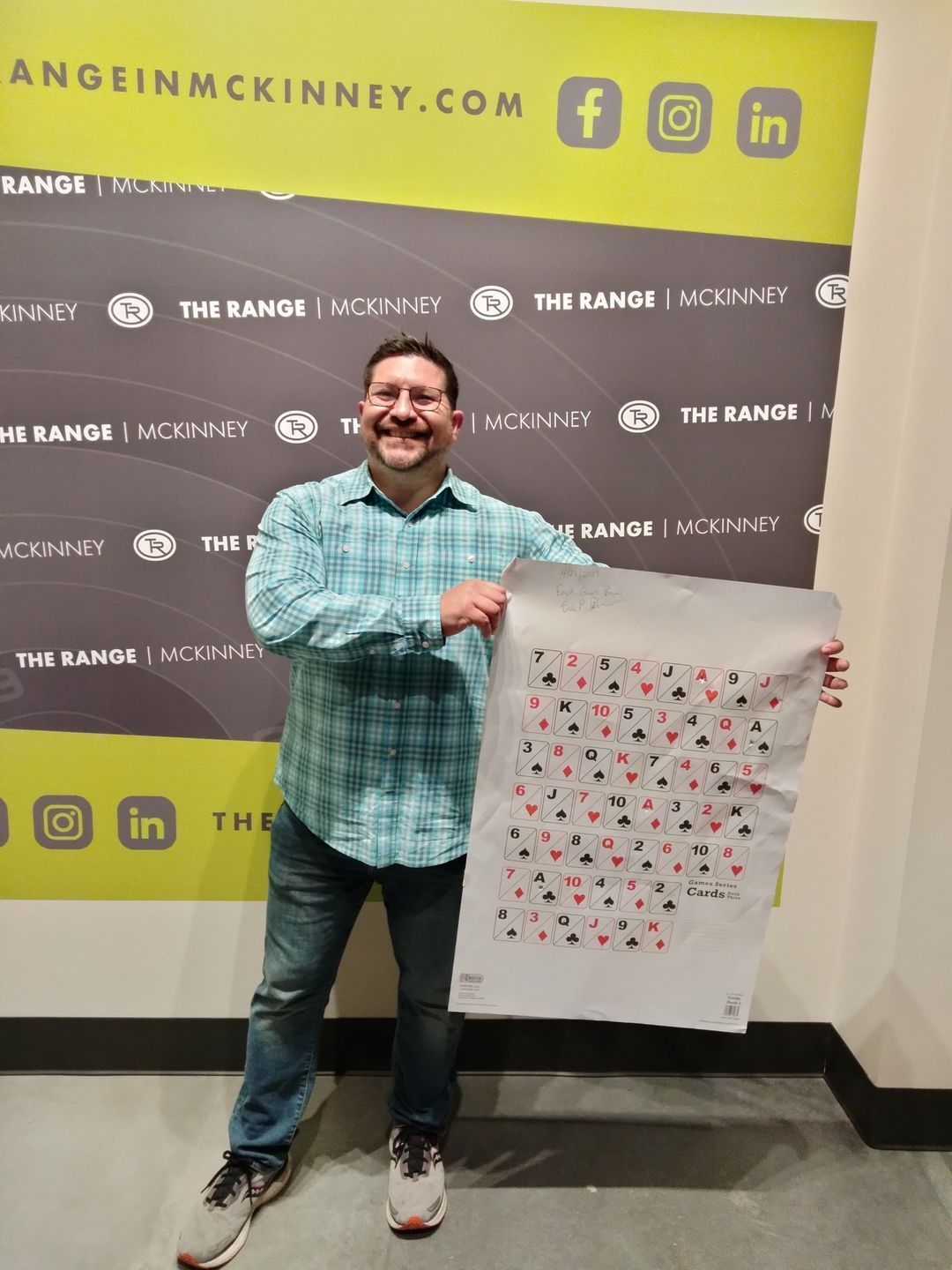 Shooter holding up a target at the branded photo wall
