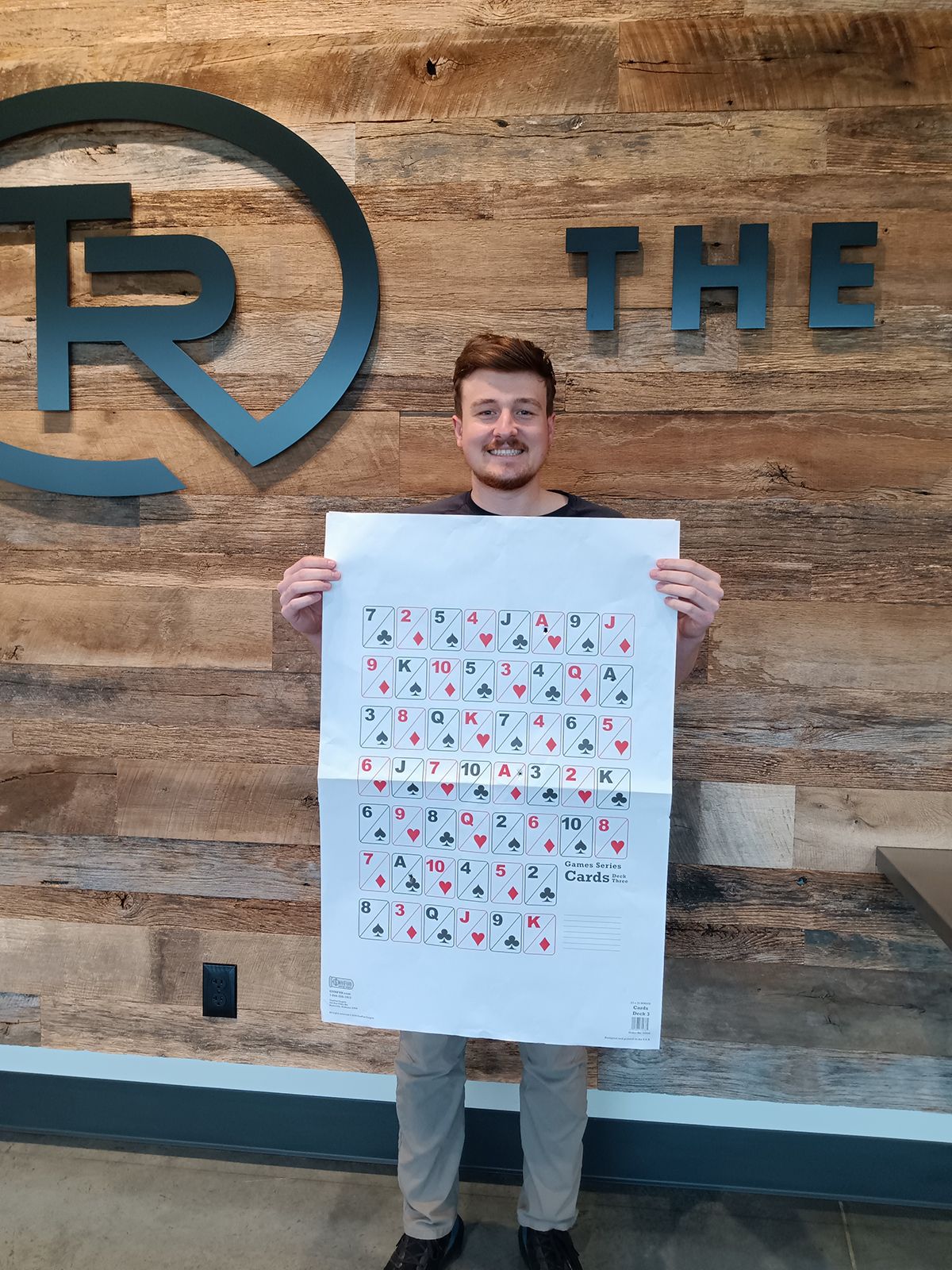 Shooter holding up his target in front of the TR logo wall
