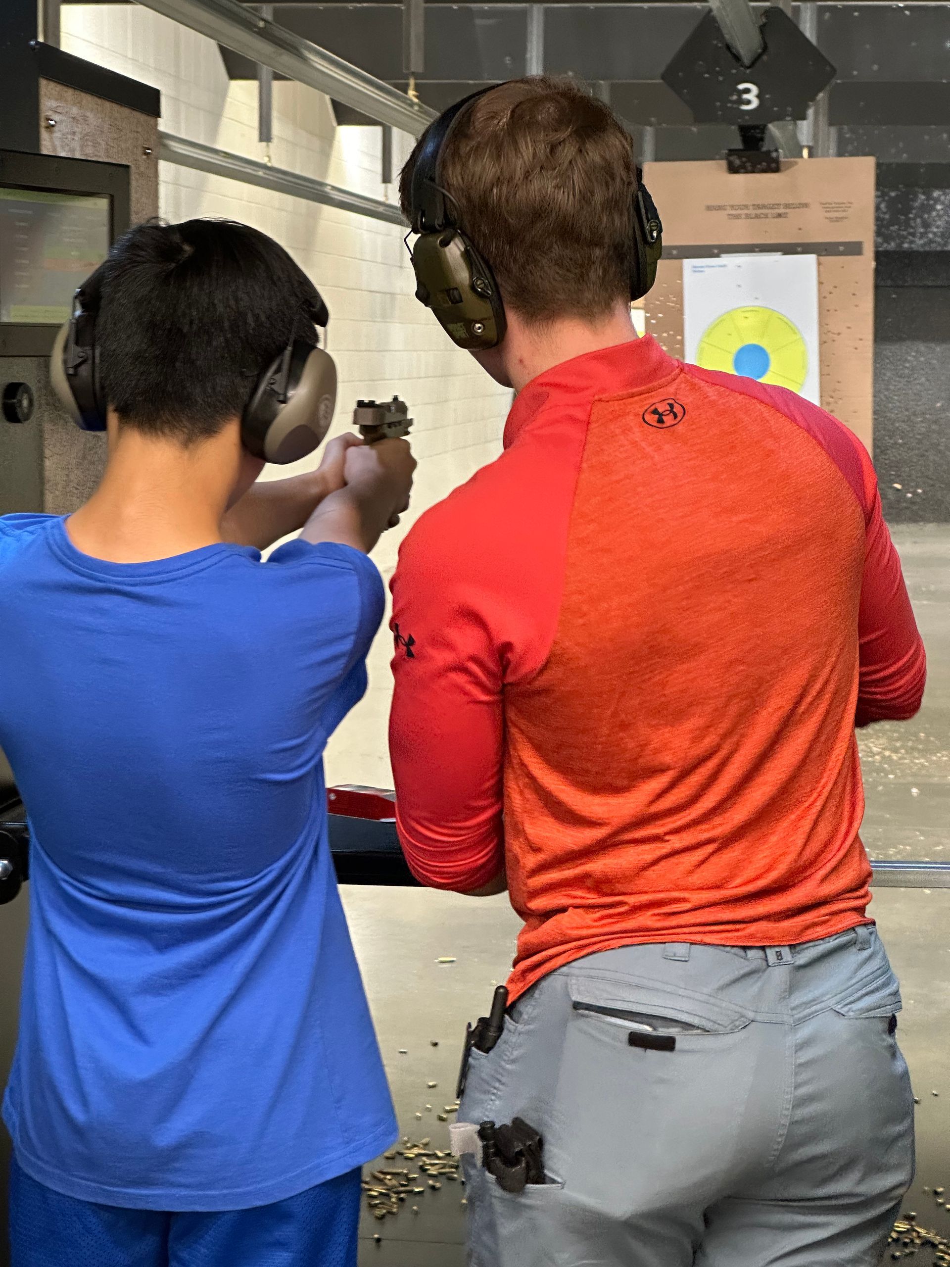 Instructor helping a young shooter aim a pistol
