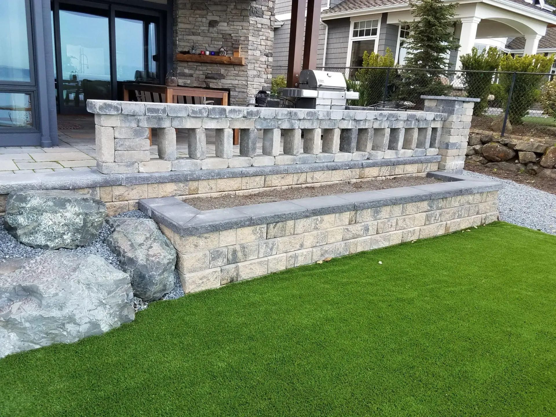 Stone front porch with steps, railing, and a bright green lawn in front of a house