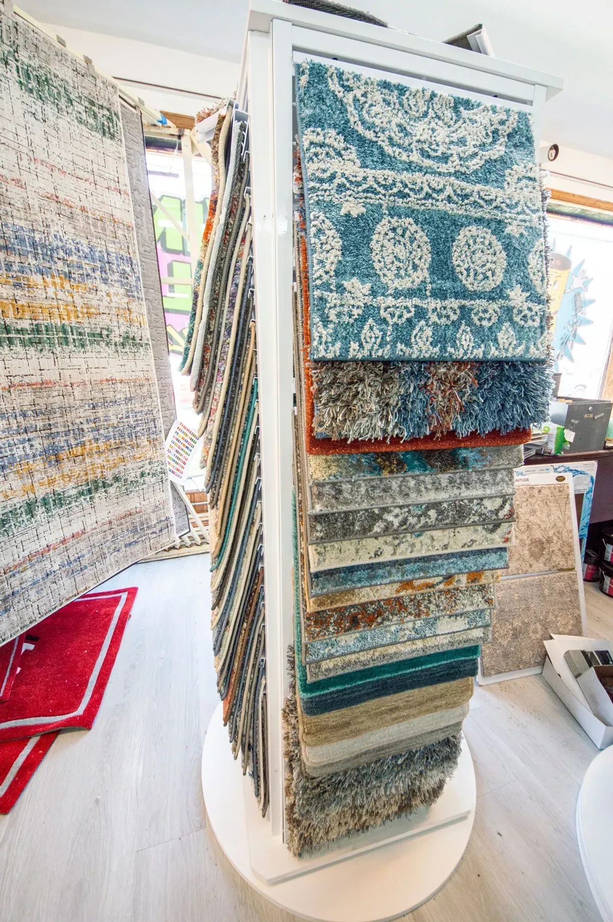 Rotating display rack showcasing various carpet samples in a store.