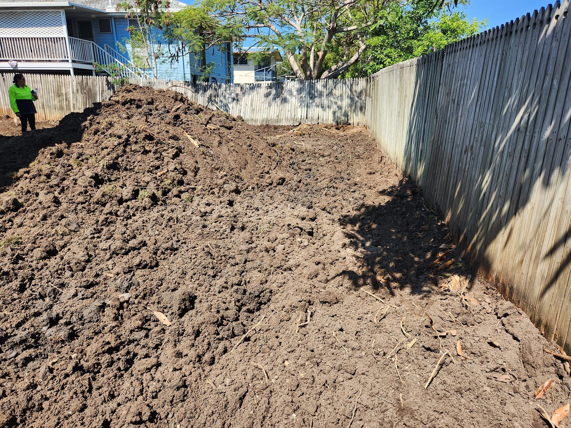 A Large Pile of Dark Brown Soil Next to a Wooden Fence — AGM HIRE NQ in Kelso, QLD