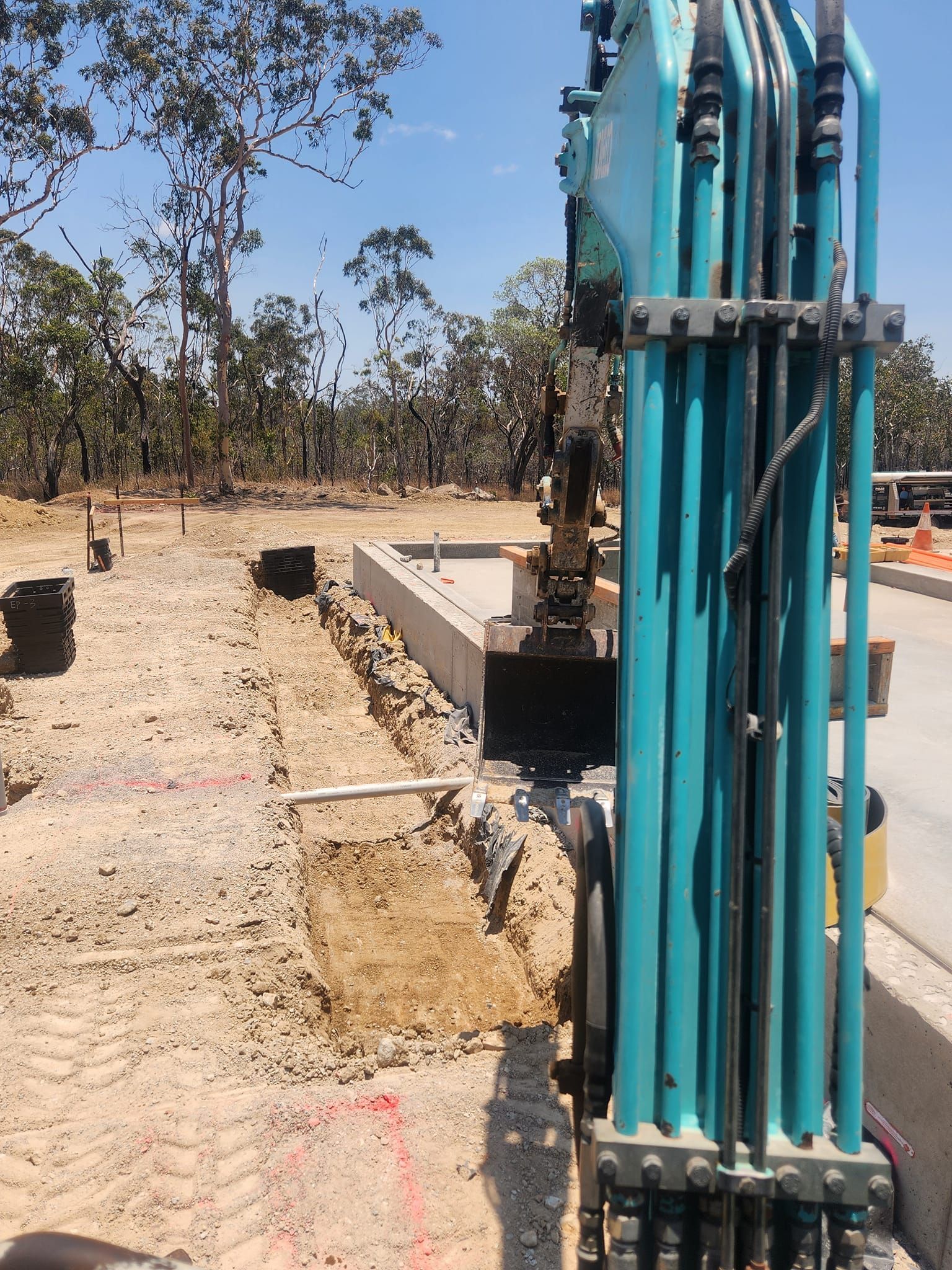 Excavator Digging Trench Beside Concrete Foundation — AGM HIRE NQ in Condon, QLD