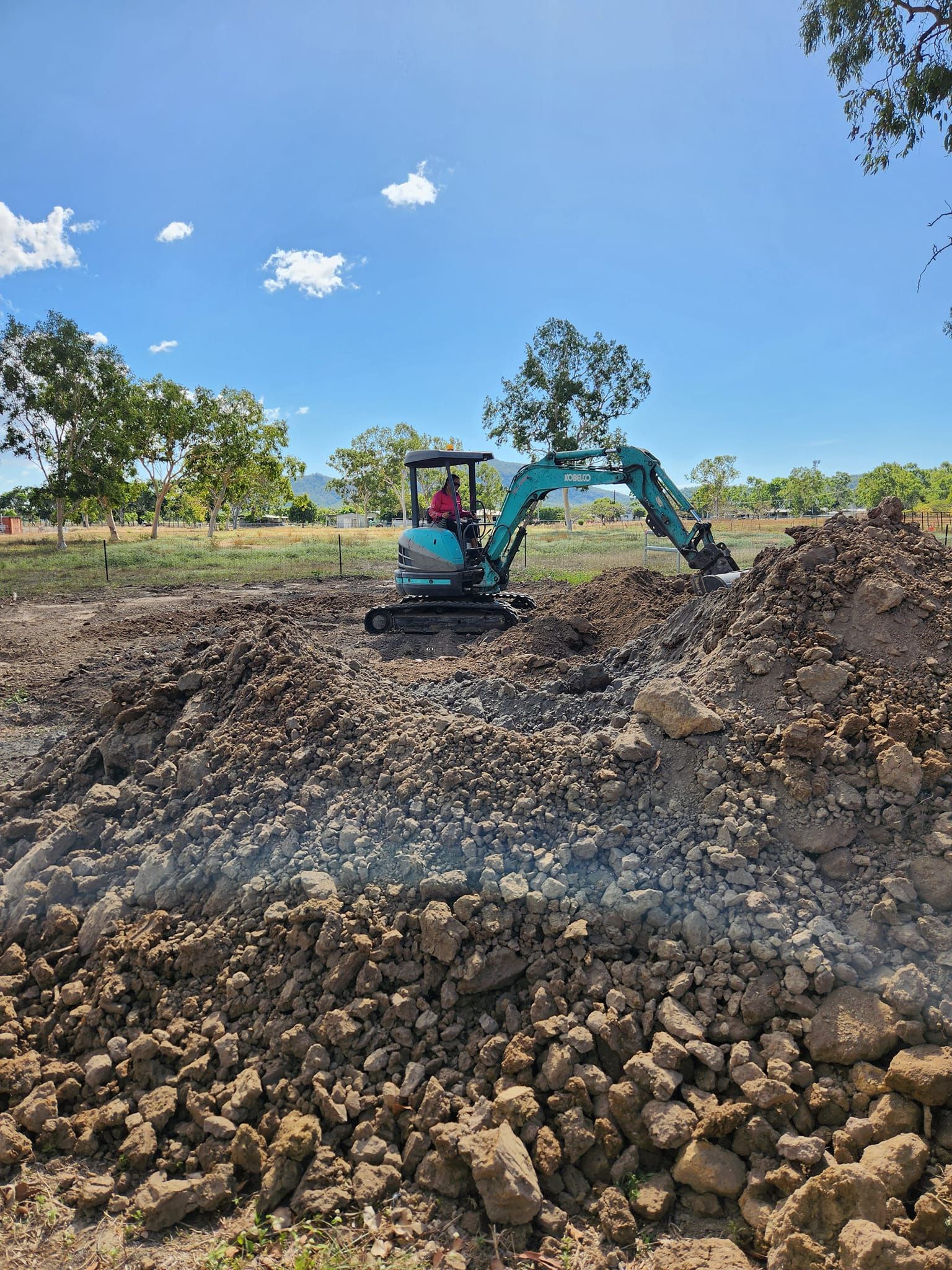 A Small Excavator Digs Into a Pile of Dirt — AGM HIRE NQ in Condon, QLD