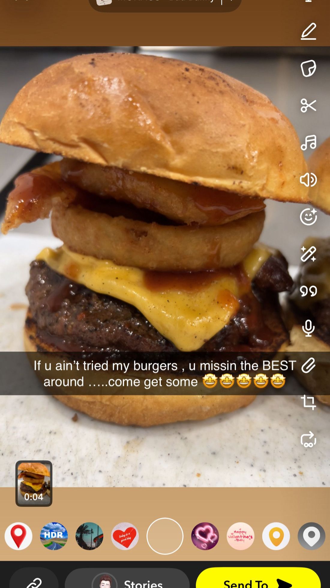 Stacked cheeseburger with two onion rings and melted cheese on a white plate.