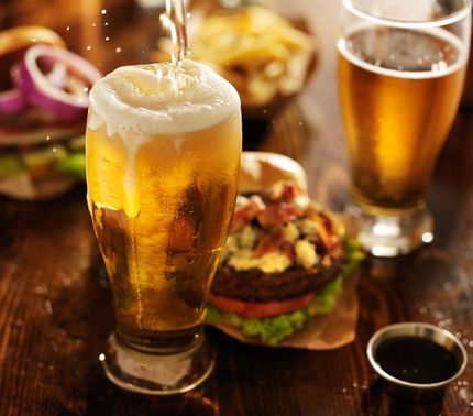 beer being poured into glass with gourmet hamburgers