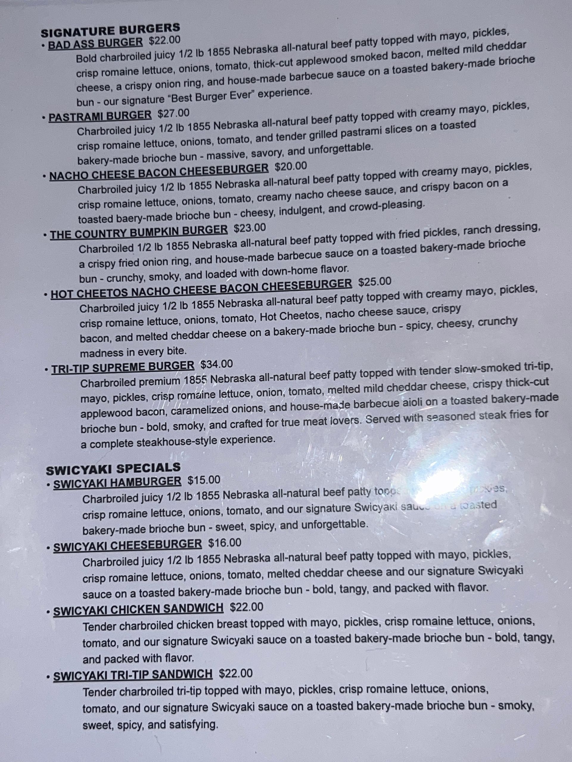 Blurry photo of a printed page with small black text and headings, lit by glare on the right side.