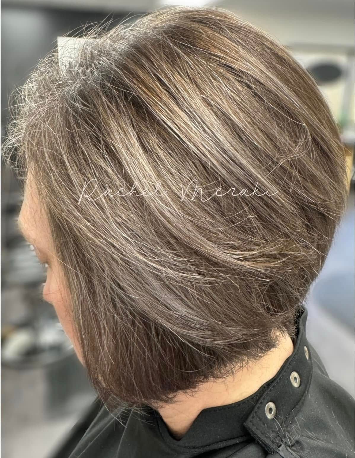 Short layered brown bob hairstyle with blonde highlights, shown from the side in a salon setting