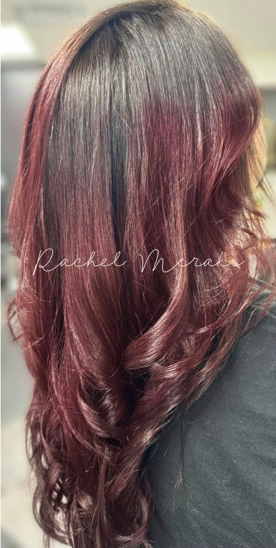 Long wavy burgundy hair with dark roots, styled in loose curls, shown from the back.