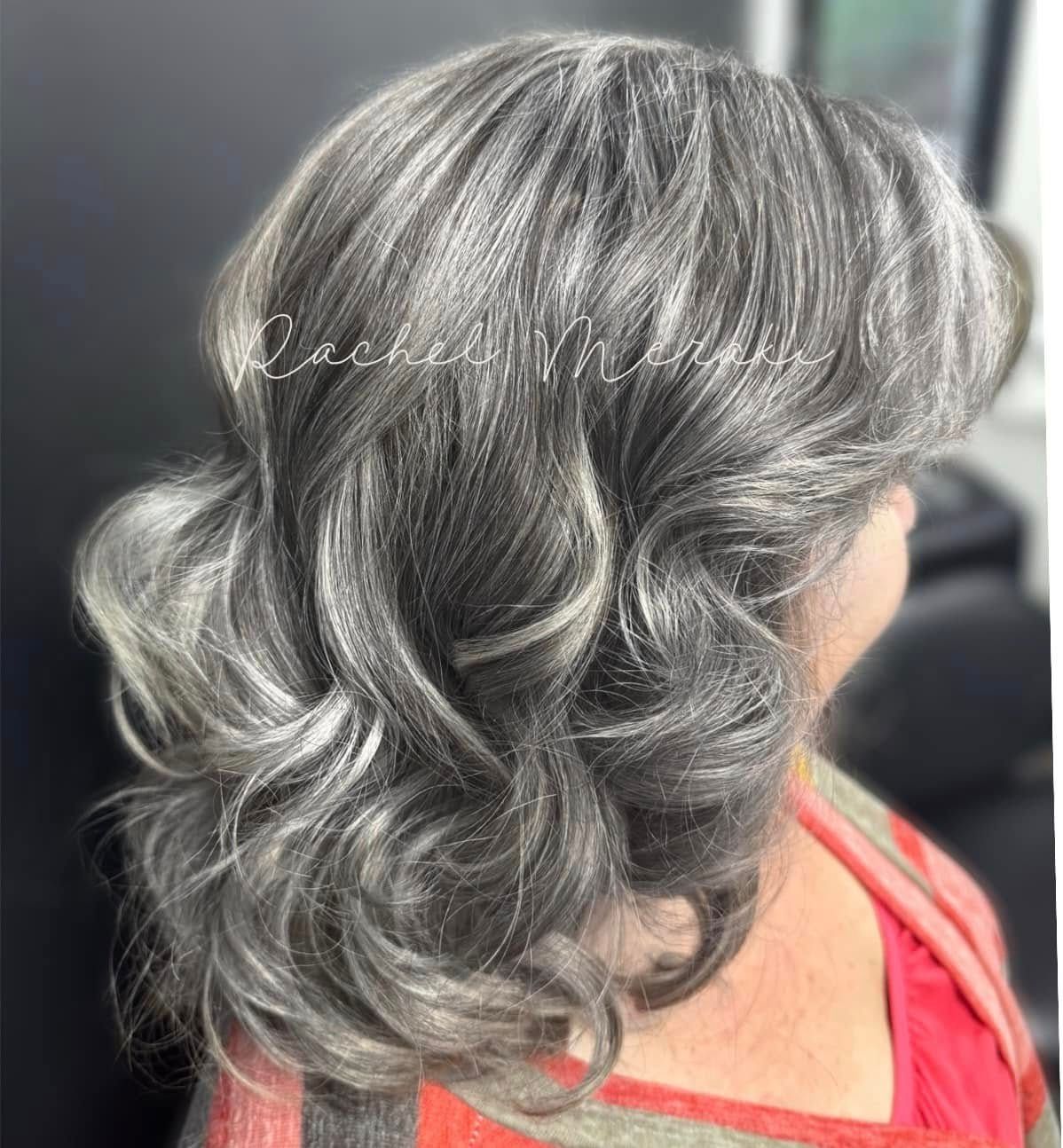 Side view of shoulder-length silver-gray wavy hair styled in soft curls and layers