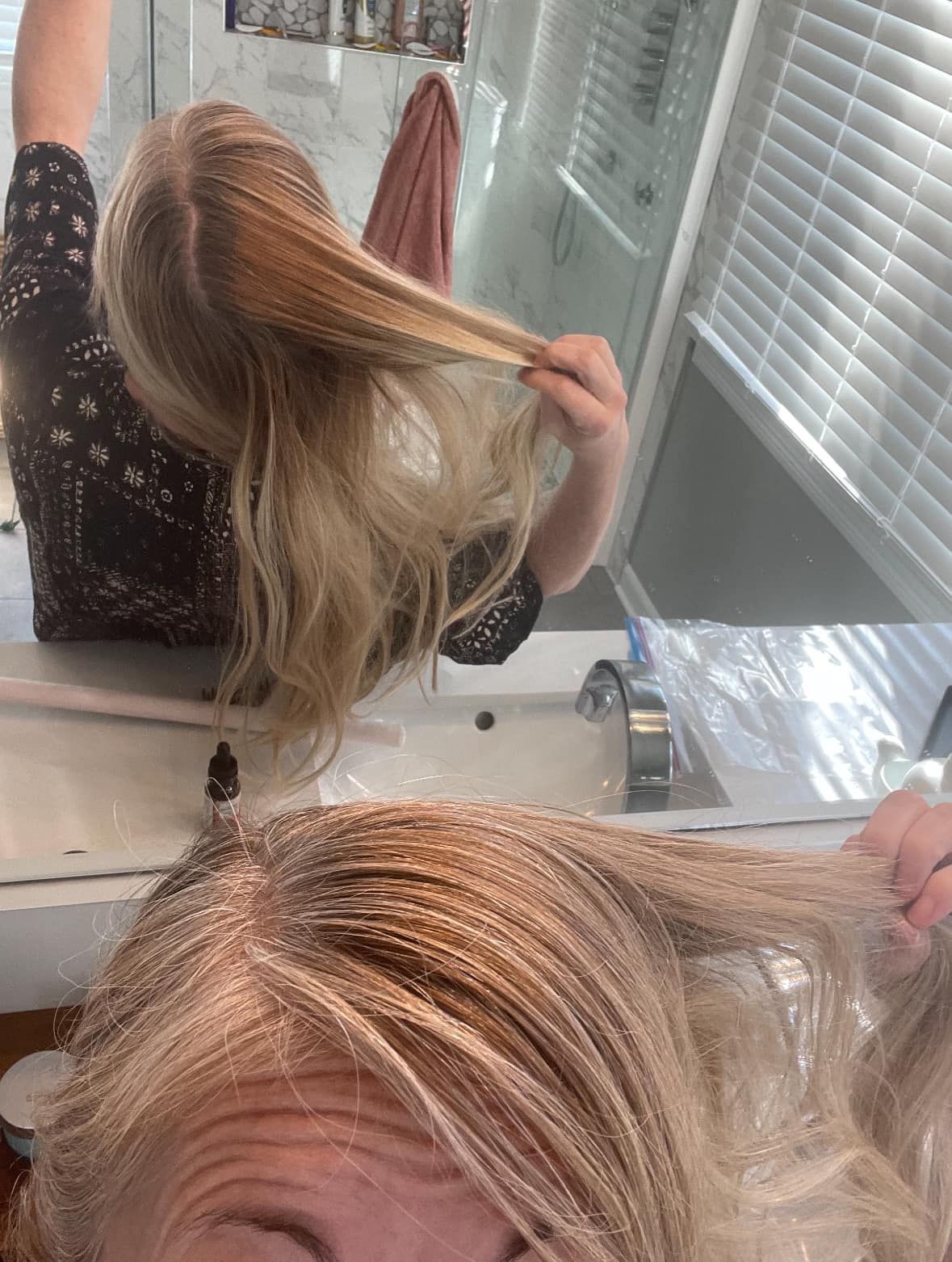 Woman in a bathroom showing long blonde hair in a mirror selfie.