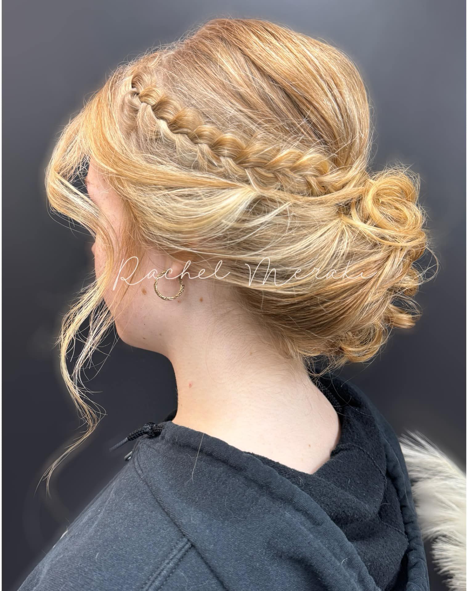 Braided blonde updo with loose curls, viewed from the side against a dark background