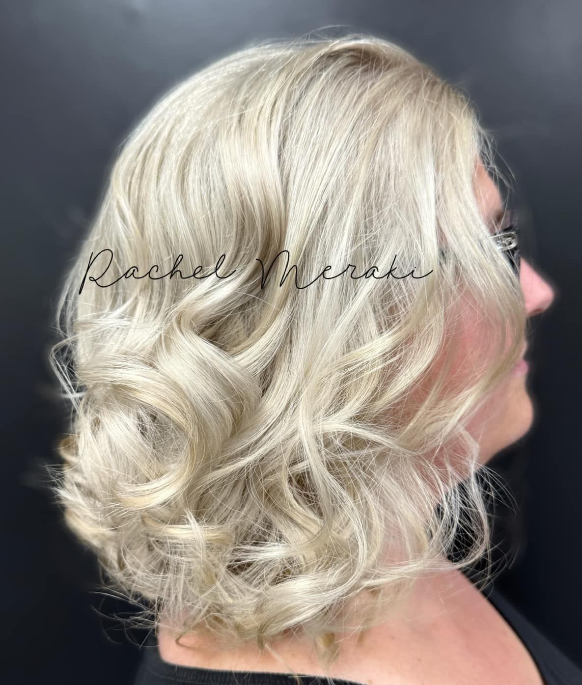 Side view of a short, wavy platinum blonde hairstyle on a black background