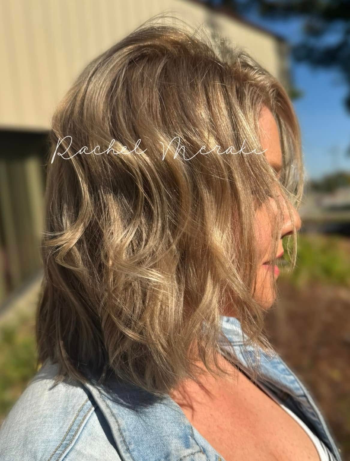 Side profile of a woman with wavy blonde hair outdoors in sunlight