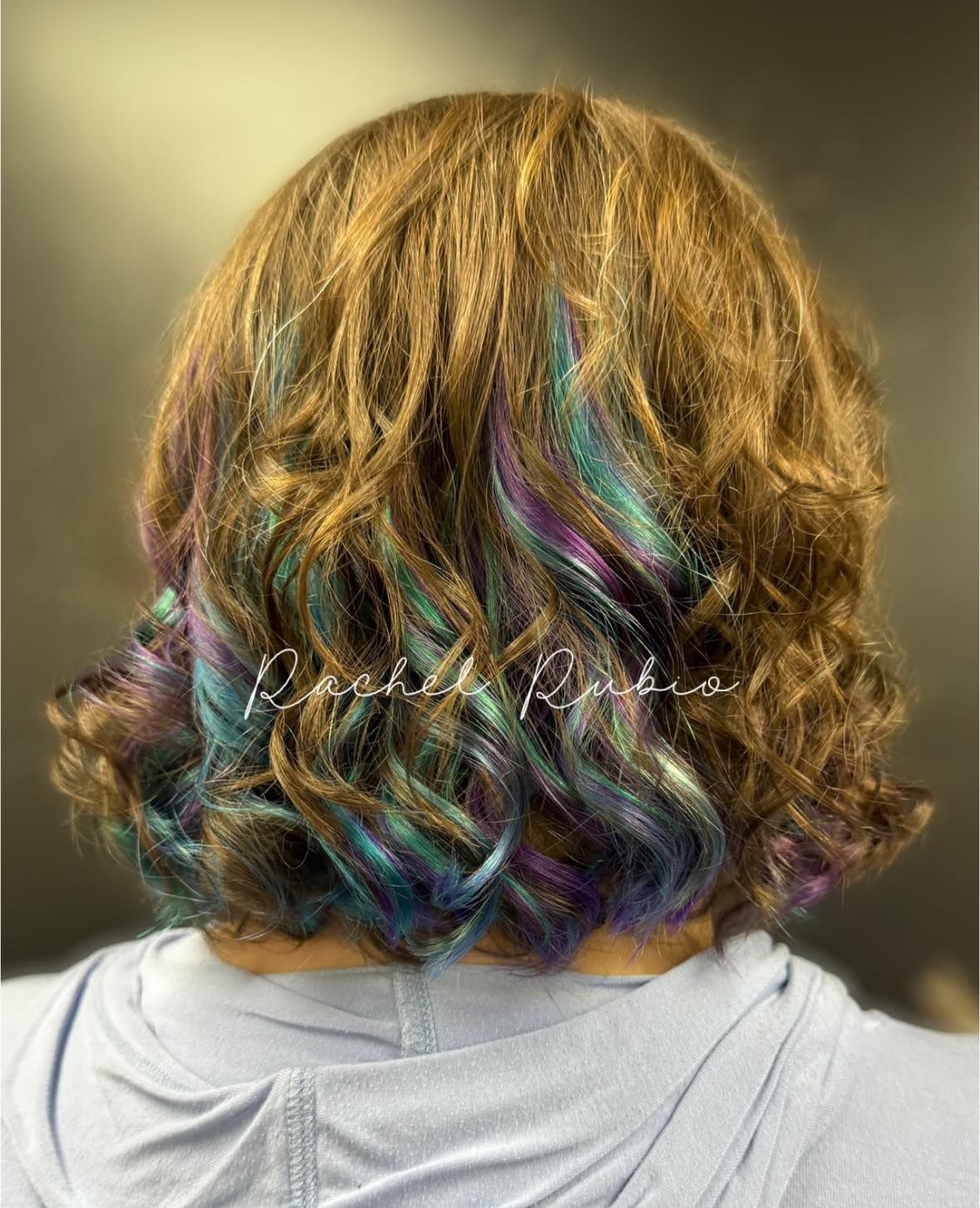 Back view of shoulder-length wavy hair with iridescent blue, purple, and pink highlights