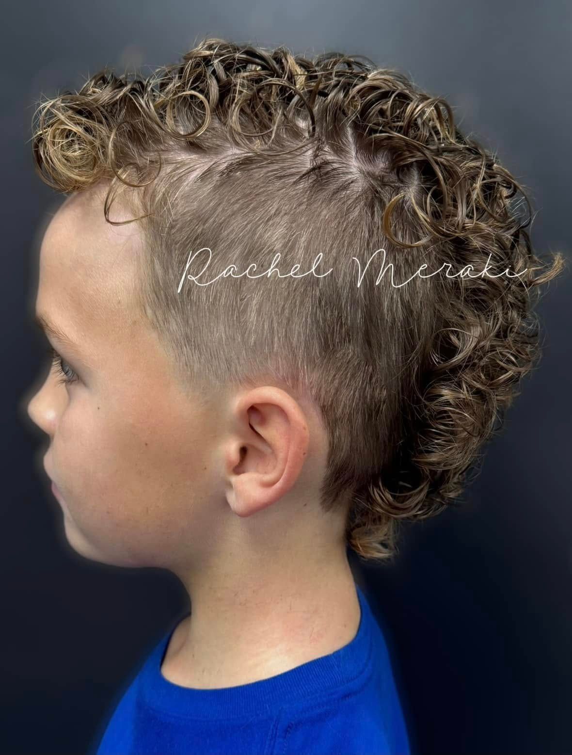 Side profile of a child with a curly mohawk haircut wearing a blue shirt against a gray background