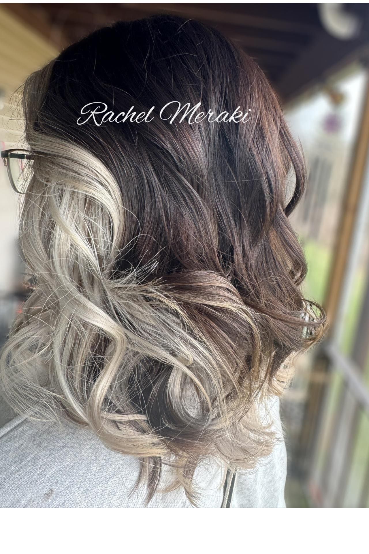 Long wavy brunette hair with blonde balayage, styled in loose curls at a salon