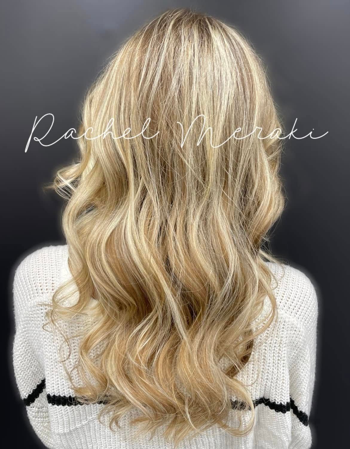 Wavy blonde balayage hairstyle viewed from the back on a dark background