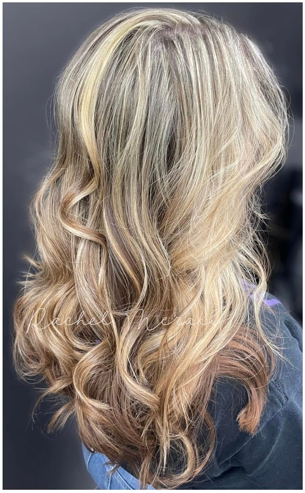 Wavy blonde hair with dark lowlights, shown from the back against a dark background