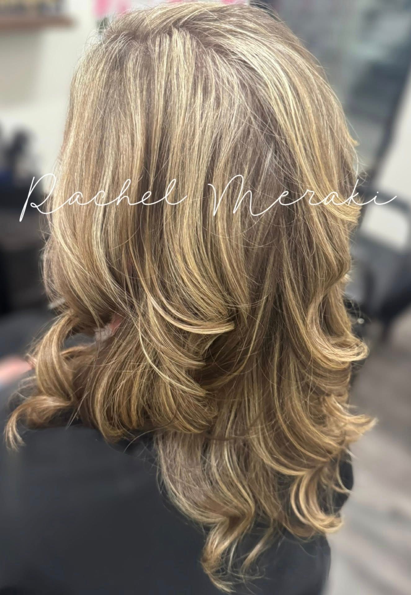 Layered blonde wavy shoulder-length hairstyle with highlighted lowlights, viewed from the back