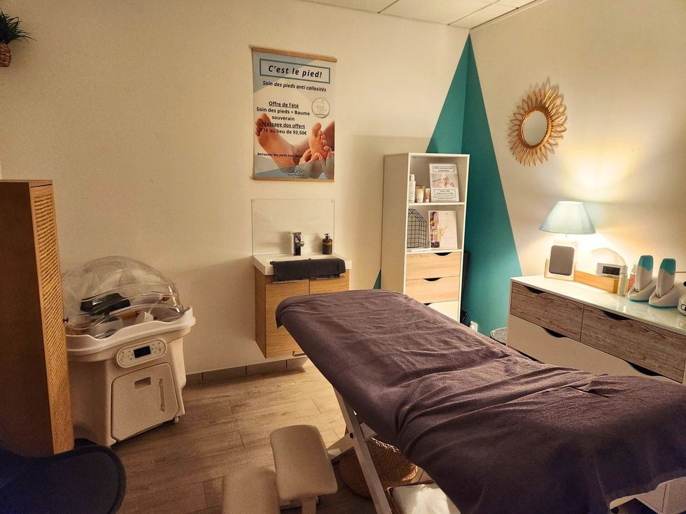 Salle de massage thérapeutique, avec table de massage, murs blancs et divers équipements de traitement.