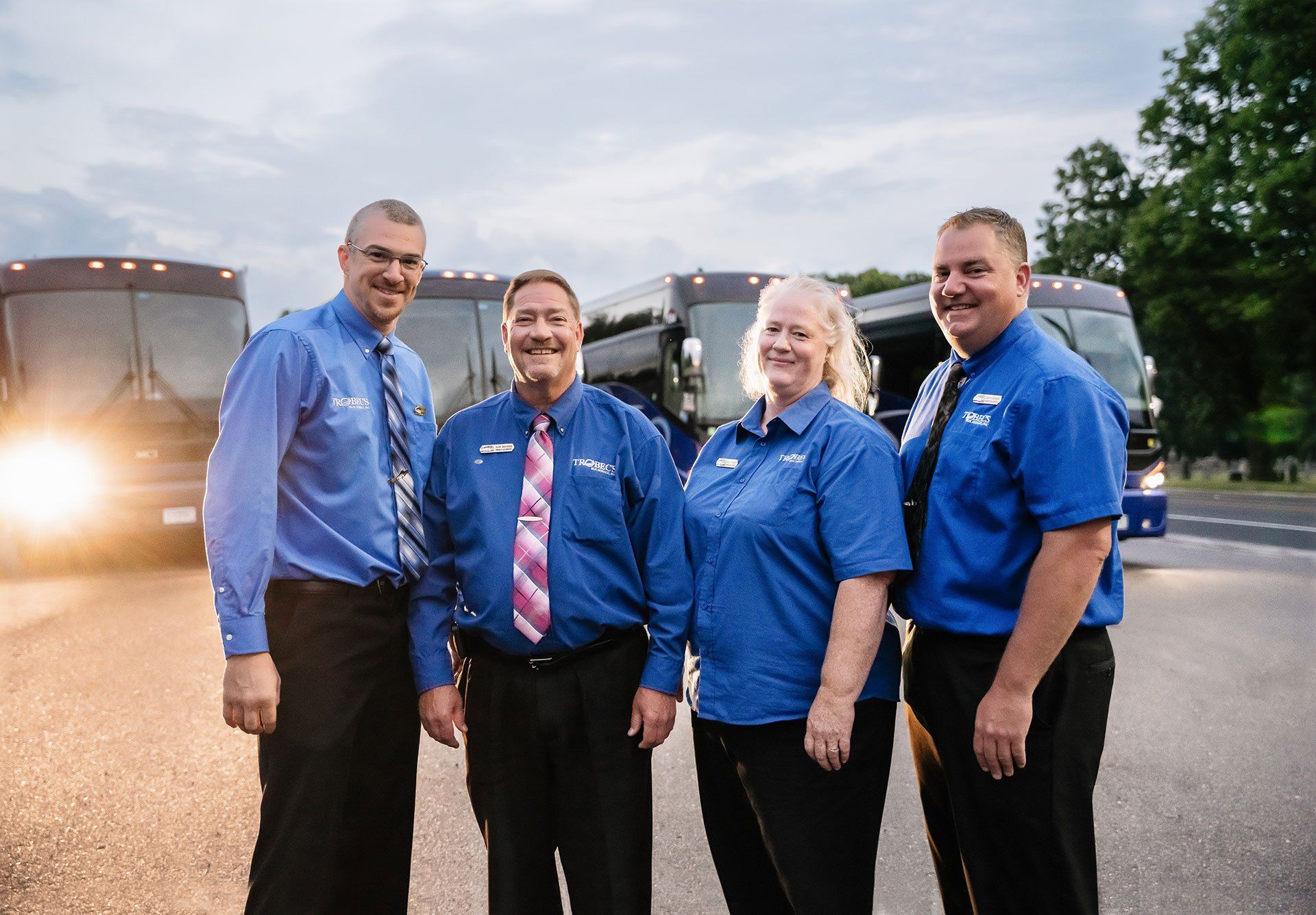 Four Motorcoach Drivers in Blue Shirts Standing in Front of Charter Vehicles in St. Cloud, MN