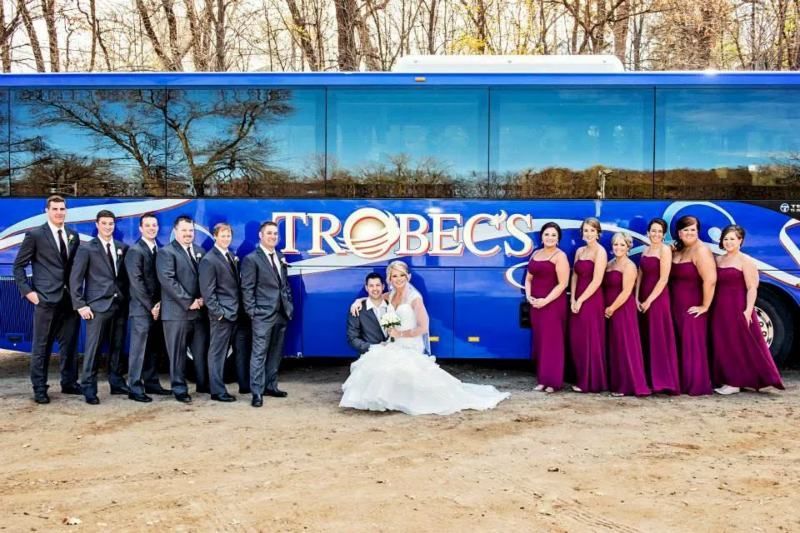 A Wedding Party Gathered in Front of a Large Blue Charter Bus Parked Outdoors in St. Cloud, MN