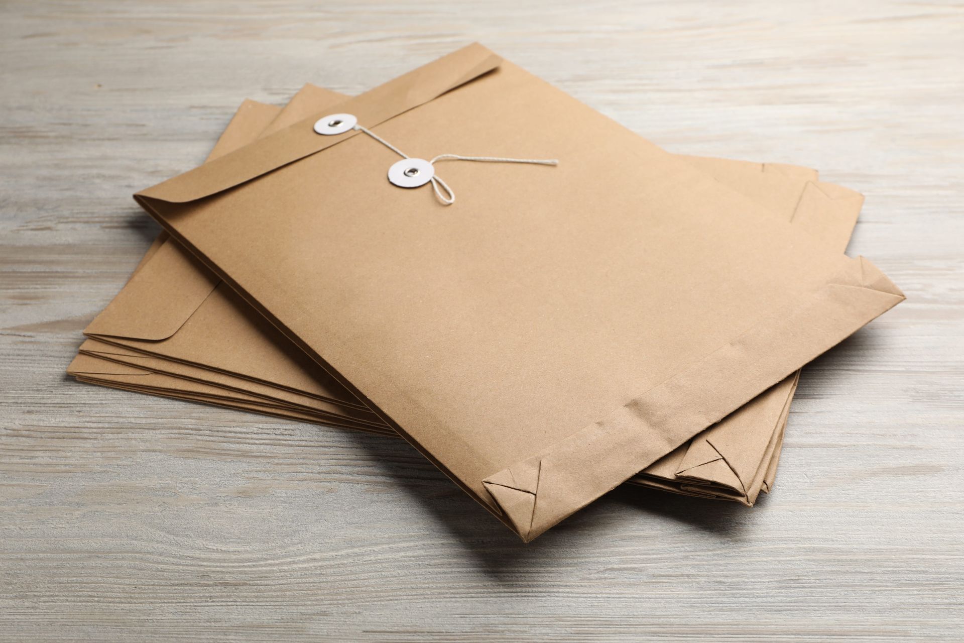 Stack of brown paper envelopes tied with string on a wooden surface