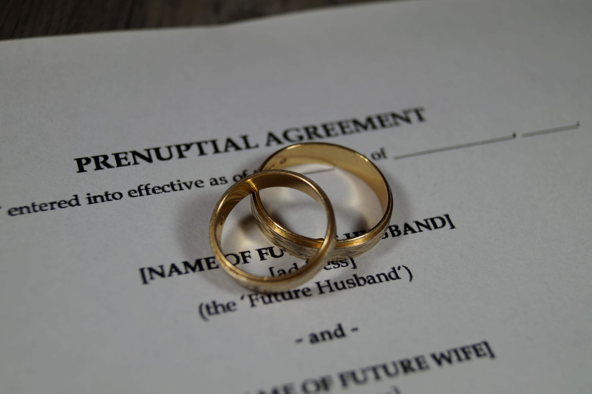 Two gold wedding rings on a prenuptial agreement document