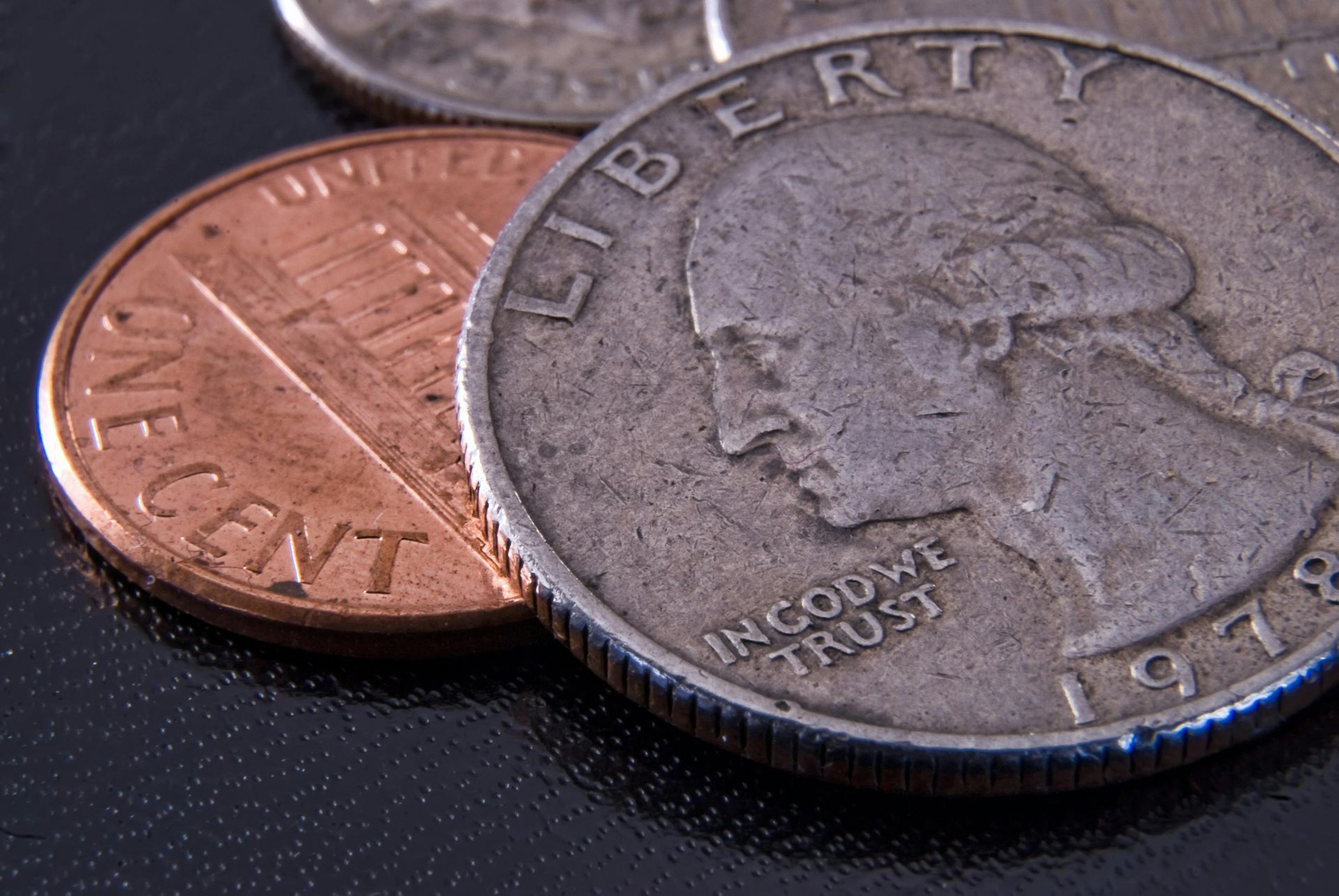 A close-up of a penny and quarter, with a small portion of a dime visible.